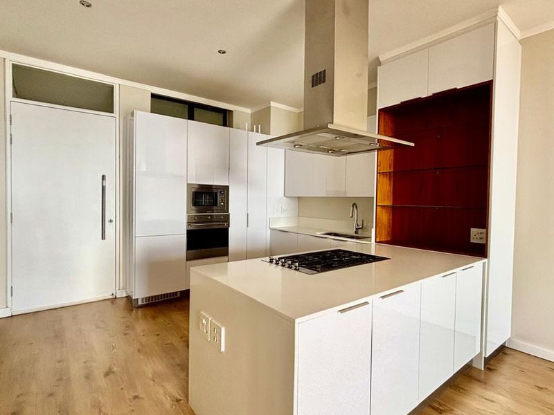 Modern kitchen featuring white high-gloss cabinetry, a central island with a gas hob, integrated appliances, and warm-toned laminate flooring.