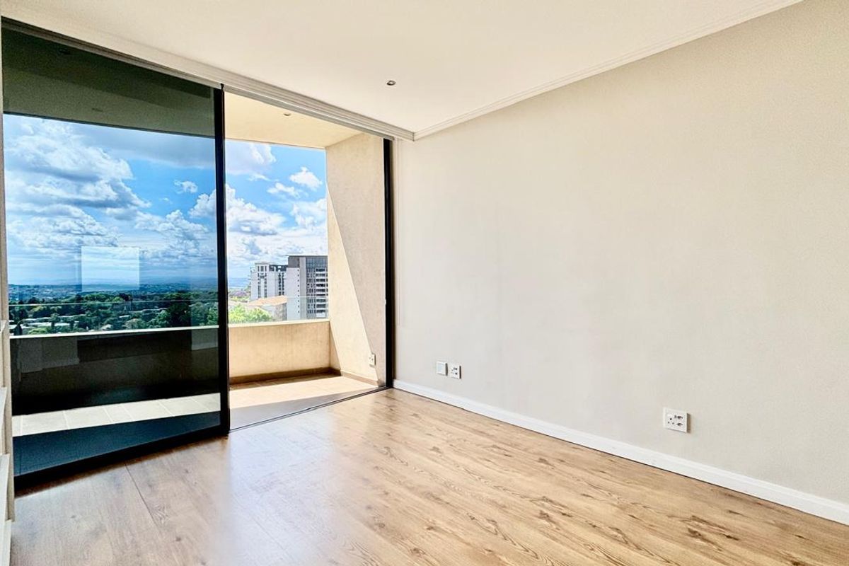 Bright and spacious living area featuring modern laminate flooring, recessed lighting, and a large sliding glass door opening onto a private balcony with city views.