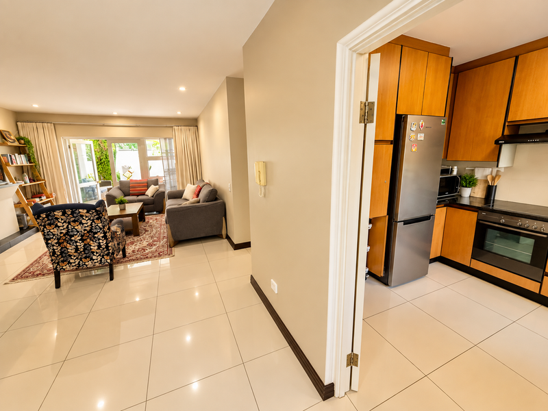 Open-plan living area featuring polished tiled floors, a modern kitchen with built-in appliances, and sliding glass doors leading to an outdoor patio space.