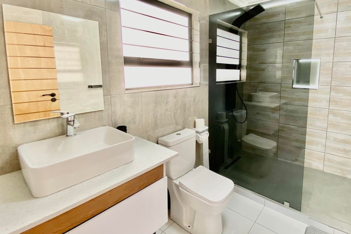 Modern bathroom featuring a vessel sink vanity, a sleek walk-in shower with glass enclosure, and contemporary neutral tiling throughout.