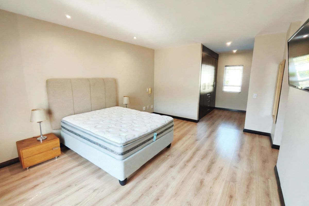 Spacious bedroom featuring light laminate flooring, recessed downlighting, and ample built-in cupboard storage.