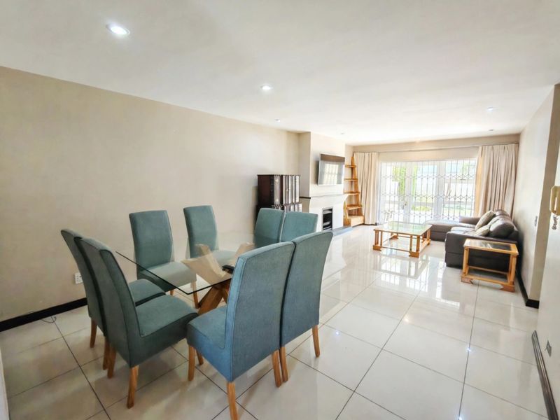 Spacious open-plan living and dining area featuring polished tiled flooring, recessed lighting, and a fireplace with direct access to the exterior through sliding doors.