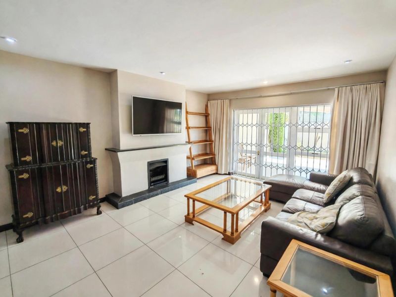 Spacious living room featuring large format floor tiles, a built-in fireplace, and sliding glass doors providing access to the outdoor area.