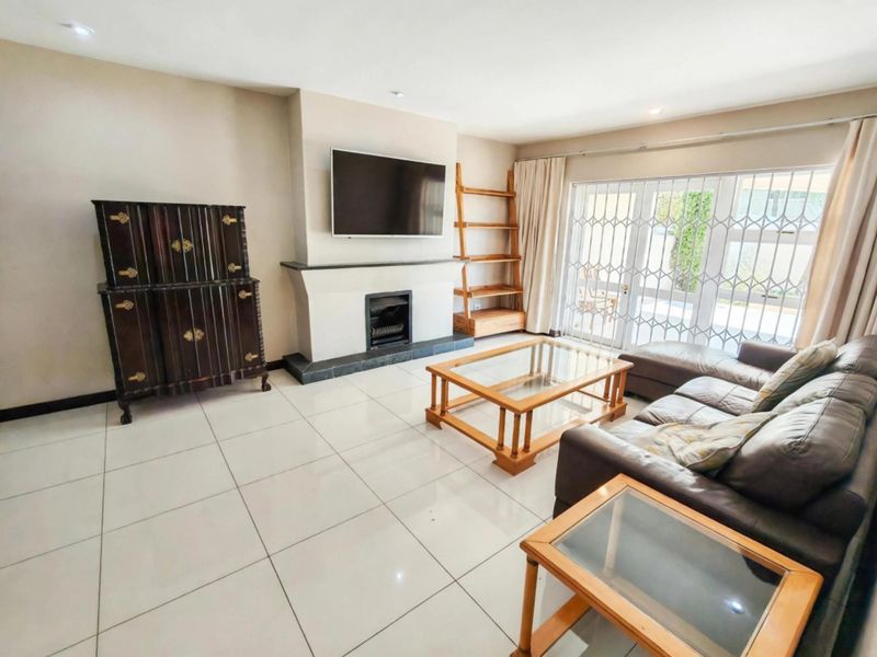 Spacious living room featuring large format floor tiles, a central fireplace, and sliding glass doors providing access to the outdoor area.