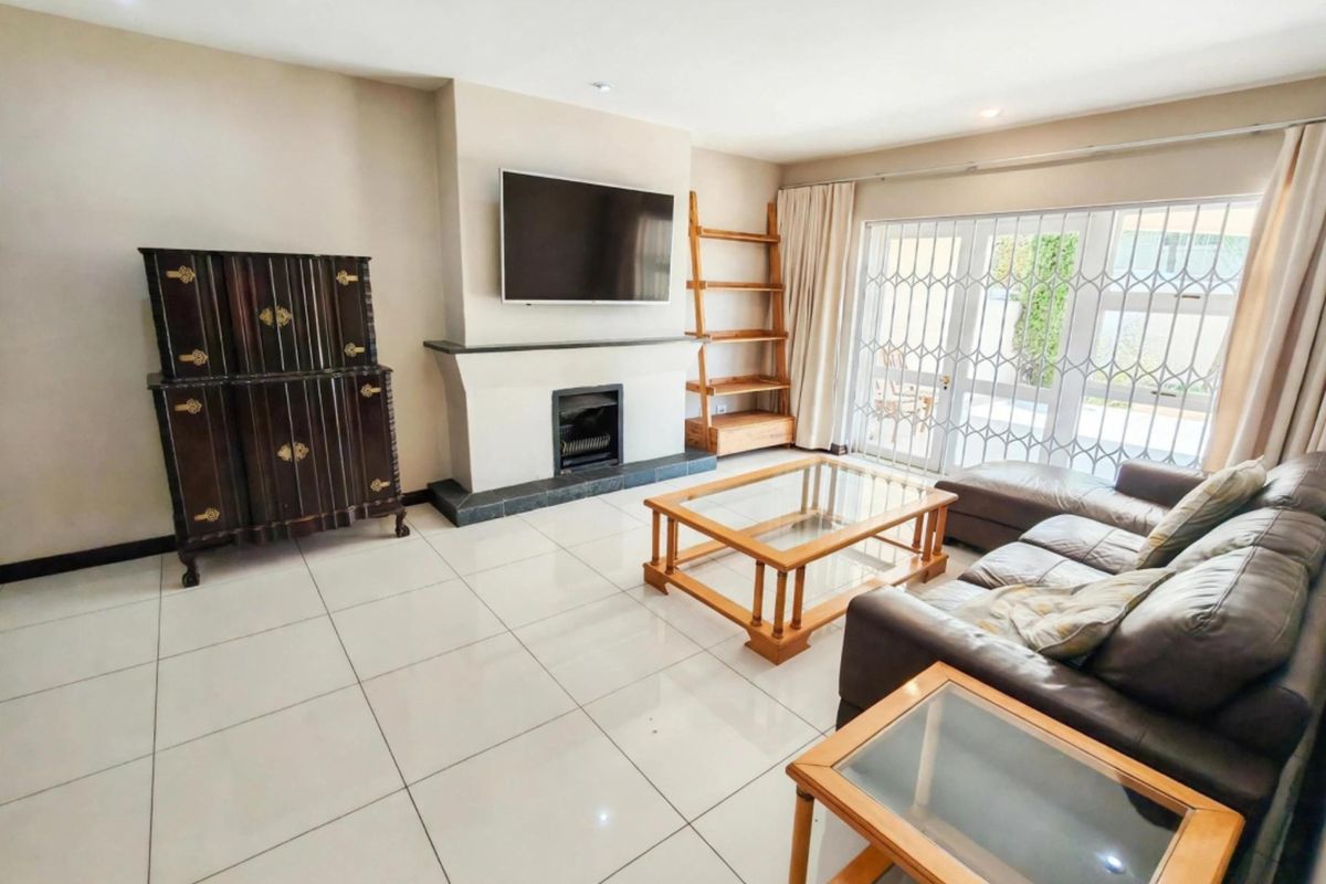 Spacious living room featuring large format floor tiles, a central fireplace, and sliding glass doors providing access to the outdoor area.