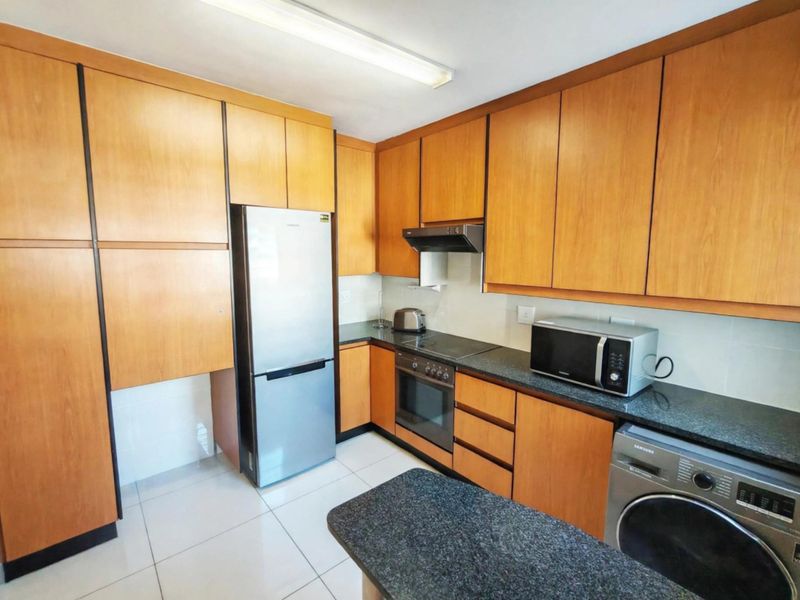 A functional kitchen featuring wood-finish cabinetry, granite countertops, and integrated appliances, offering a practical layout for daily cooking and meal preparation.
