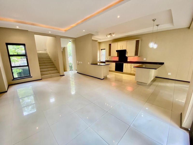 Spacious open-plan living and kitchen area featuring modern tiled floors, recessed ceiling lighting, and a well-appointed kitchen with granite countertops and built-in appliances.