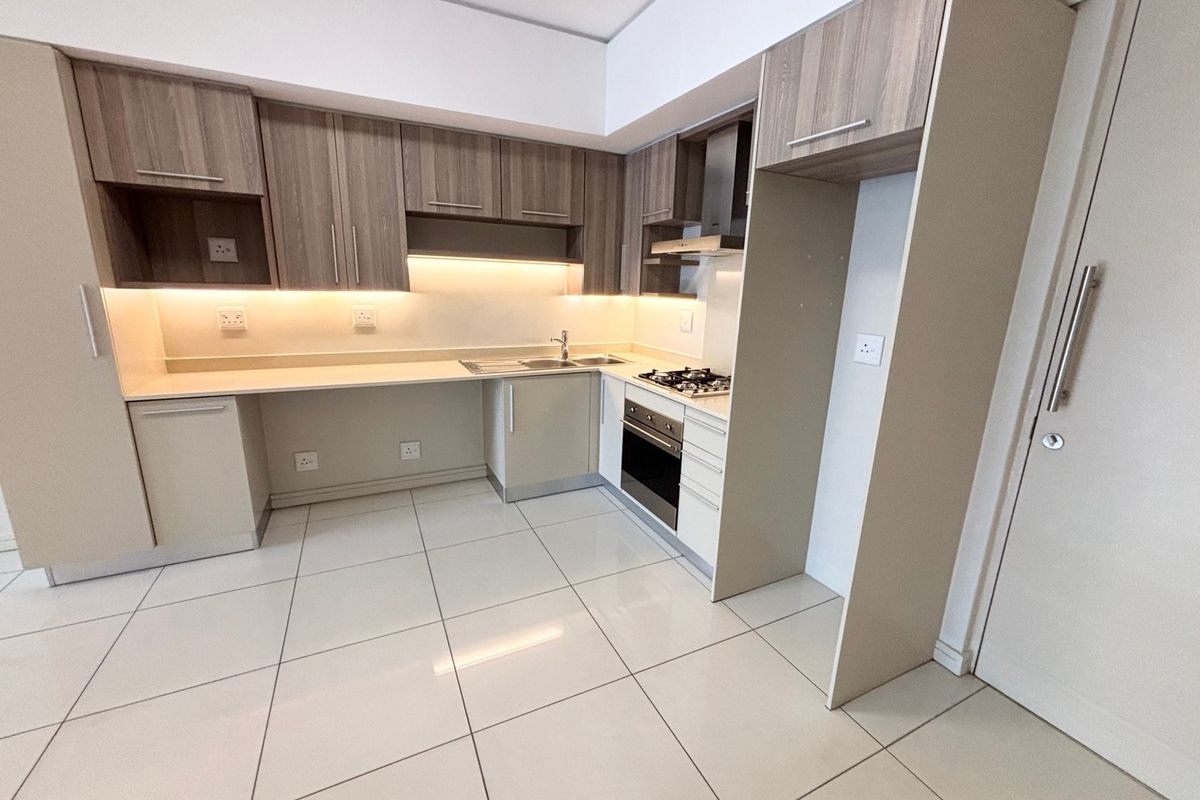 Modern kitchen featuring sleek built-in cabinetry, stone countertops, integrated oven and hob, and high-quality tiled flooring in a clean, contemporary layout.