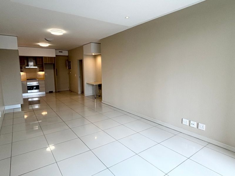 Spacious open-plan living area featuring large format floor tiles, recessed lighting, and a modern kitchen with integrated stainless steel appliances.