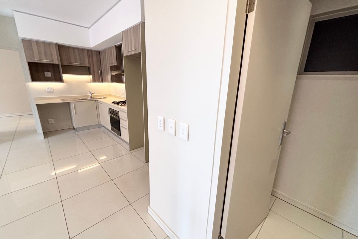 Modern kitchen featuring sleek built-in cabinetry, integrated appliances, under-cabinet lighting, and polished tiled flooring in an open-plan layout.