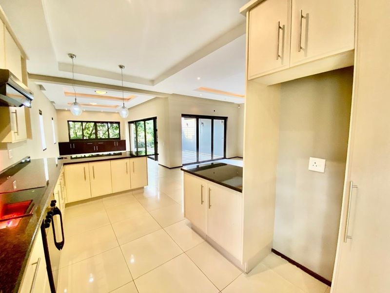 Spacious open-plan kitchen and living area featuring modern cabinetry, granite countertops, tiled flooring, and large sliding doors leading to the outdoor space.