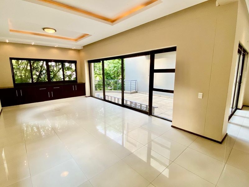 Spacious, light-filled living area featuring polished tile floors, recessed ceiling lighting, and large sliding glass doors opening onto an outdoor patio.