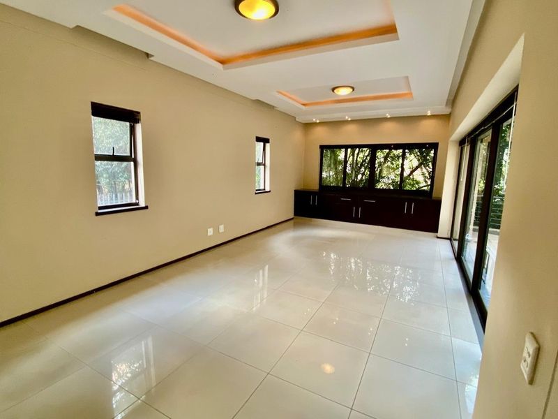 Spacious, light-filled living area featuring polished tile flooring, recessed ceiling lighting, built-in cabinetry, and large sliding glass doors leading to the exterior.