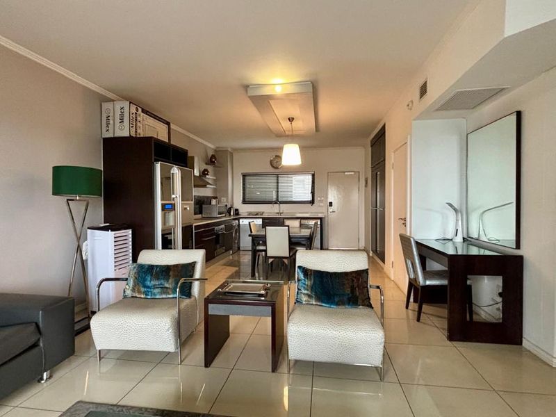 Open-plan living and kitchen area featuring tiled flooring, modern cabinetry, and a dedicated built-in workspace, offering a functional and well-lit layout.