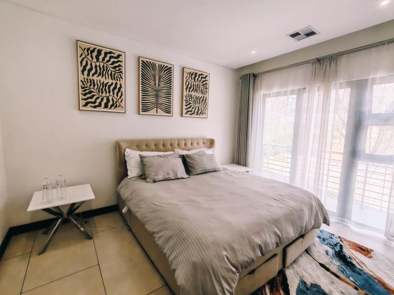 A well-maintained bedroom featuring tiled flooring, recessed lighting, and a large sliding glass door providing access to a balcony.