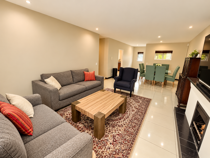 Spacious open-plan living and dining area featuring polished porcelain floor tiles, recessed downlighting, and a modern built-in fireplace with a black marble hearth.