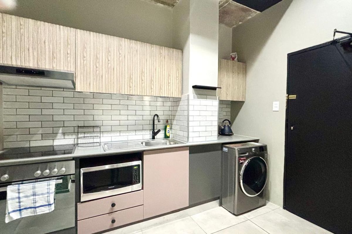 Modern kitchen featuring light wood-grain cabinetry, subway tile backsplash, integrated appliances, and tiled flooring, with an industrial-style exposed ceiling finish.