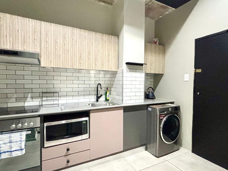 Modern kitchen featuring light wood-grain cabinetry, subway tile backsplash, integrated appliances, and tiled flooring, with an industrial-style exposed ceiling finish.