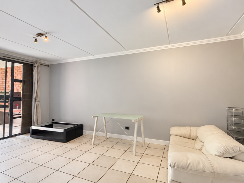 Spacious living area featuring tiled flooring, crown molding, and large sliding glass doors that provide direct access to an outdoor patio space.