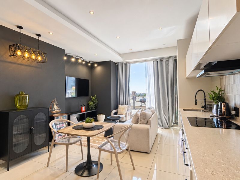 Modern open-plan living area featuring a sleek kitchen with stone countertops, induction hob, and integrated cabinetry, flowing seamlessly into a bright, contemporary lounge space.