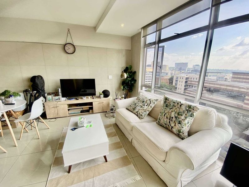 Bright living room featuring large floor-to-ceiling windows with urban views, tiled flooring, and a modern recessed ceiling design.