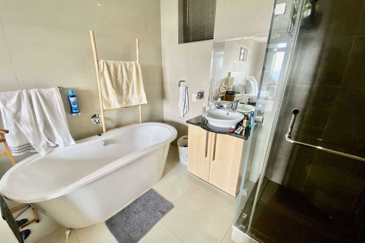 Modern bathroom featuring a freestanding bathtub, a vanity with a vessel sink, and a separate glass-enclosed shower with neutral wall and floor tiling.