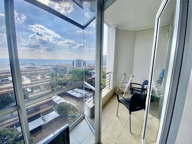 A private balcony featuring tiled flooring, a metal balustrade, and expansive glass doors offering elevated urban views.