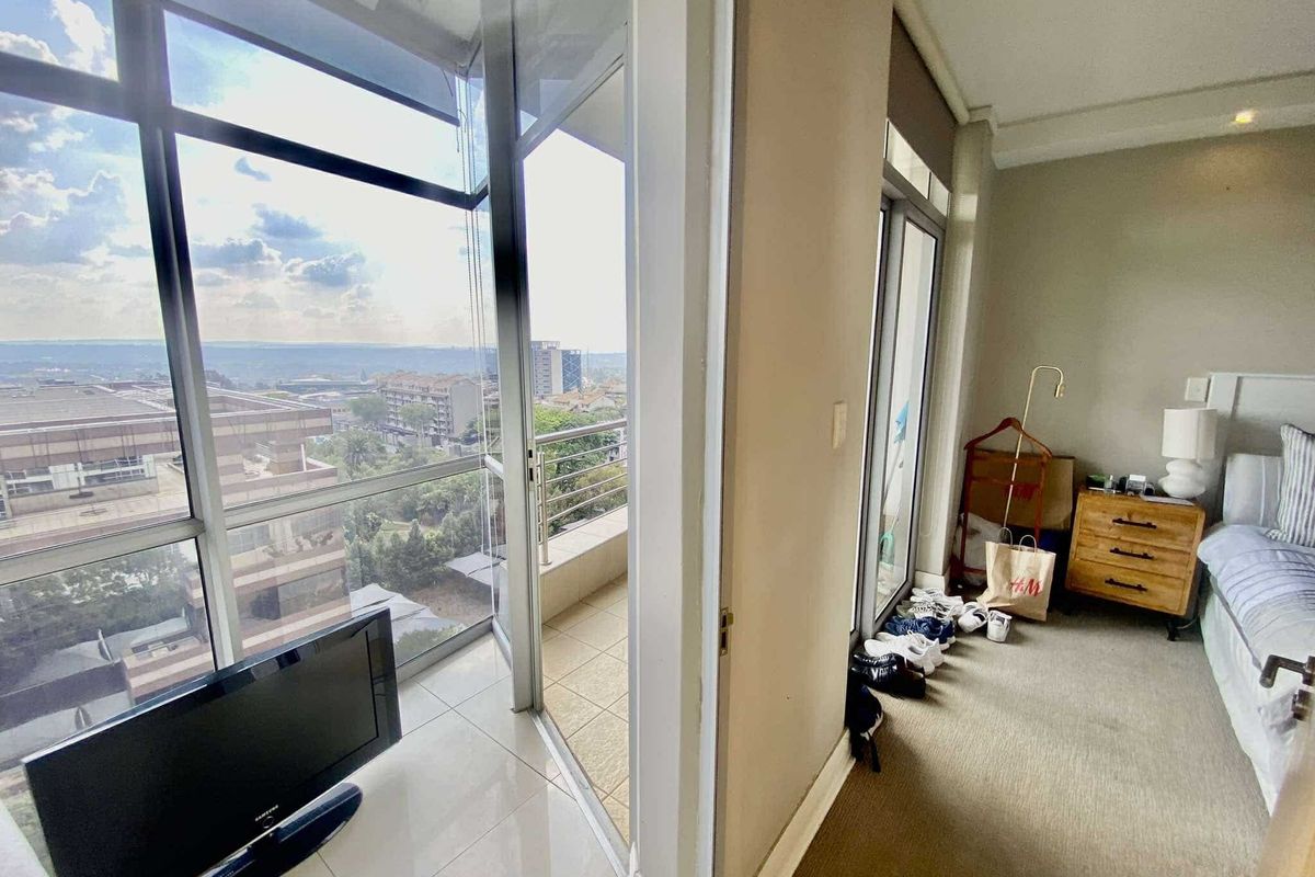 A bedroom featuring floor-to-ceiling windows and a sliding glass door leading to a private balcony with expansive city views.