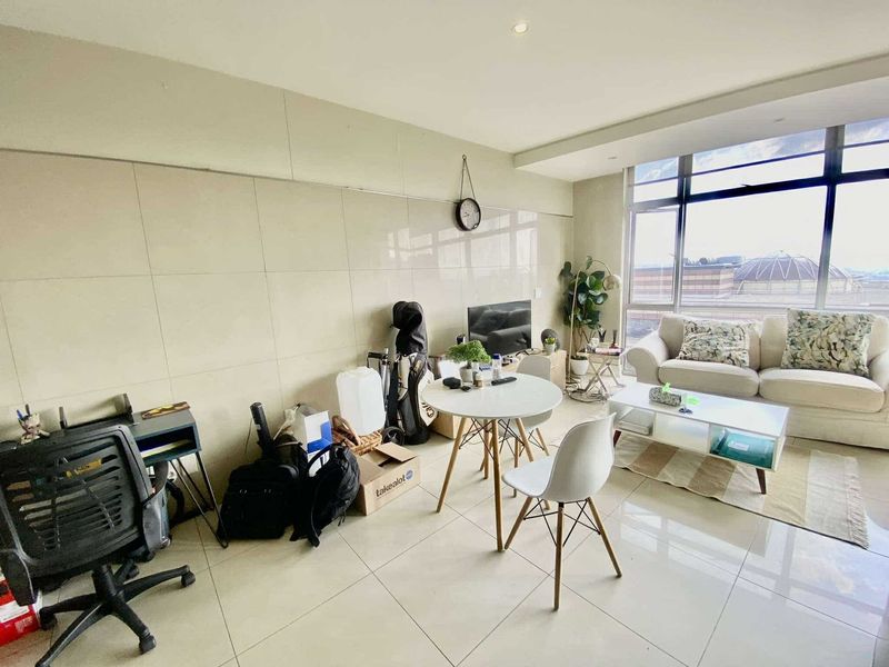 A bright living area featuring large format tiled flooring, wall tiling, and expansive floor-to-ceiling windows providing ample natural light.