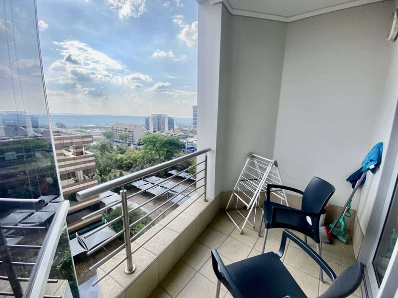 A private balcony featuring tiled flooring and a stainless steel balustrade, offering elevated urban views.