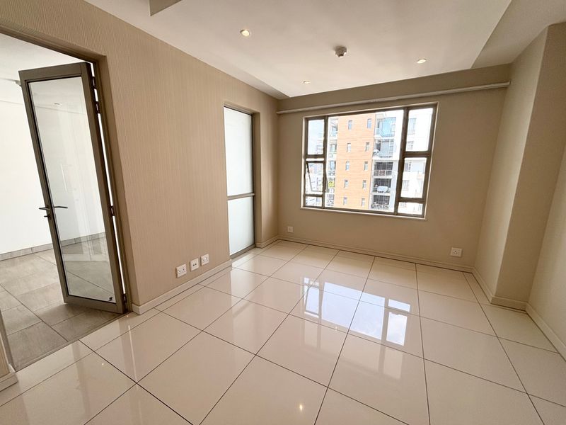 A bright, empty bedroom featuring polished tile flooring, textured wall finishes, recessed ceiling lights, and large windows providing natural light.