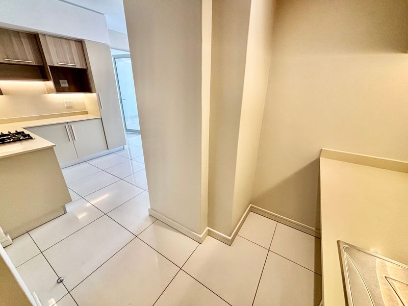 Modern kitchen featuring sleek built-in cabinetry, stone countertops, integrated gas hob, and polished tiled flooring in a clean, minimalist layout.