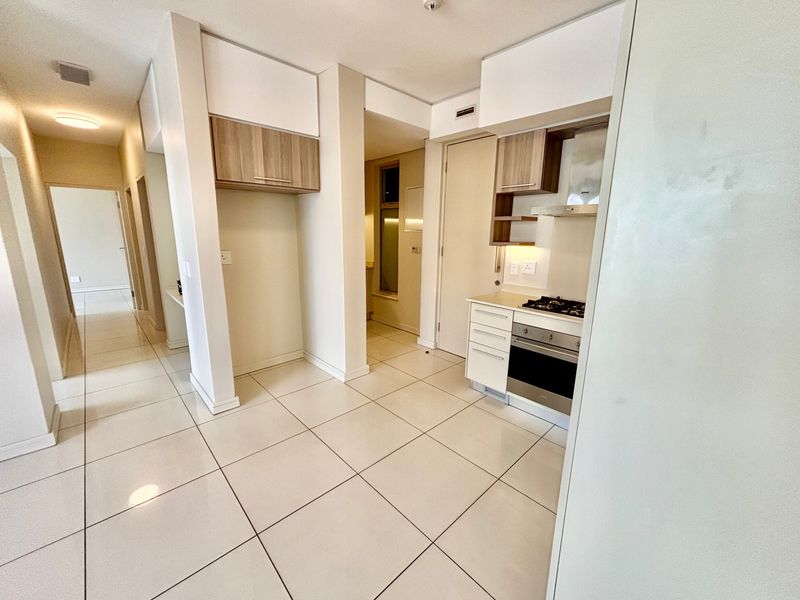 A clean, modern kitchen featuring built-in cabinetry, a gas hob, an oven, and an extractor fan, complemented by neutral tiled flooring throughout.