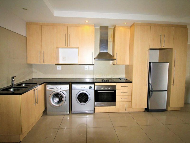 A functional kitchen featuring light wood cabinetry, granite countertops, integrated appliances, and tiled flooring, offering a clean and practical layout.