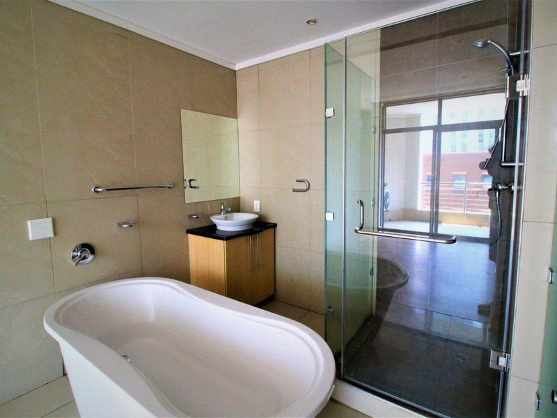 Modern bathroom featuring a freestanding bathtub, glass-enclosed shower, and a sleek vanity with a vessel sink, finished with neutral wall and floor tiles.