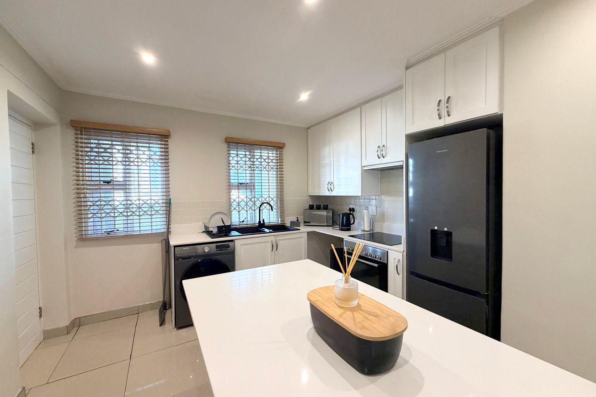 Modern kitchen featuring white cabinetry, quartz countertops, integrated appliances, tiled flooring, and recessed lighting, offering a clean and functional workspace.