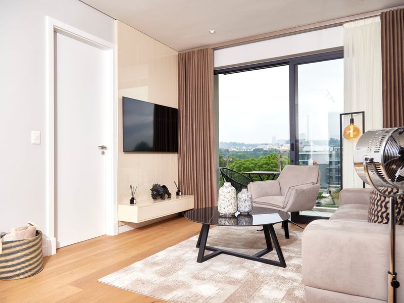 Modern living room featuring engineered wood flooring, a sleek built-in media console, and large sliding glass doors opening to a balcony with scenic views.
