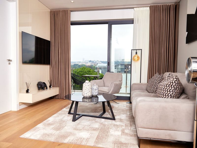 Modern living room featuring hardwood flooring, recessed lighting, and a large sliding glass door leading to a balcony with city views.