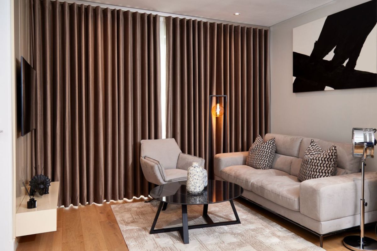 A well-appointed living room featuring hardwood flooring, recessed downlighting, and full-length curtain tracks, creating a polished and comfortable atmosphere.