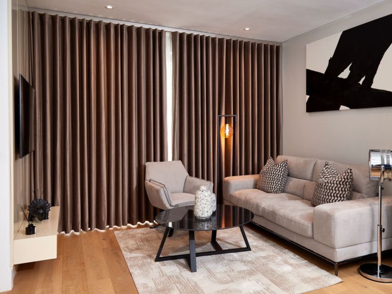 A well-appointed living room featuring hardwood flooring, recessed downlighting, and full-length curtain tracks, creating a polished and comfortable atmosphere.