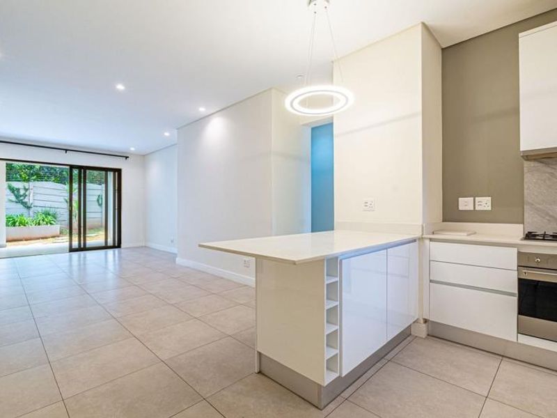 Modern open-plan living area featuring a sleek kitchen with stone countertops, built-in appliances, and large sliding doors leading to an outdoor space.