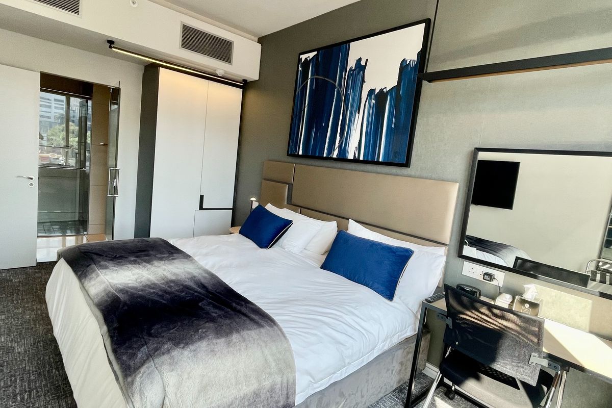 Modern bedroom featuring a built-in wardrobe, integrated air conditioning unit, and an attached ensuite bathroom with glass door access.