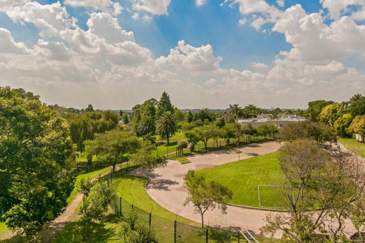 Elevated aerial view of the property grounds, featuring landscaped gardens, paved pathways, and mature trees within a well-maintained estate setting.
