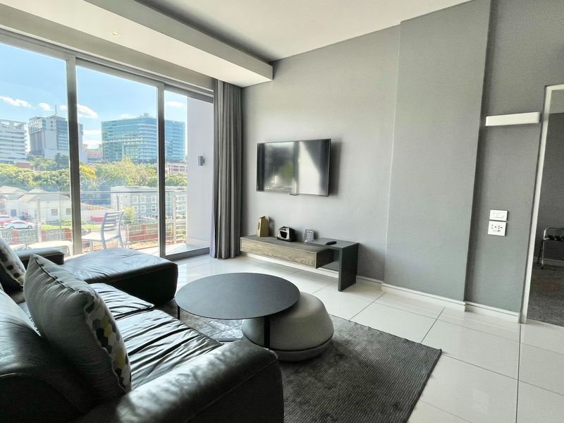Modern living room featuring large floor-to-ceiling sliding doors that provide ample natural light and access to a balcony with urban views.