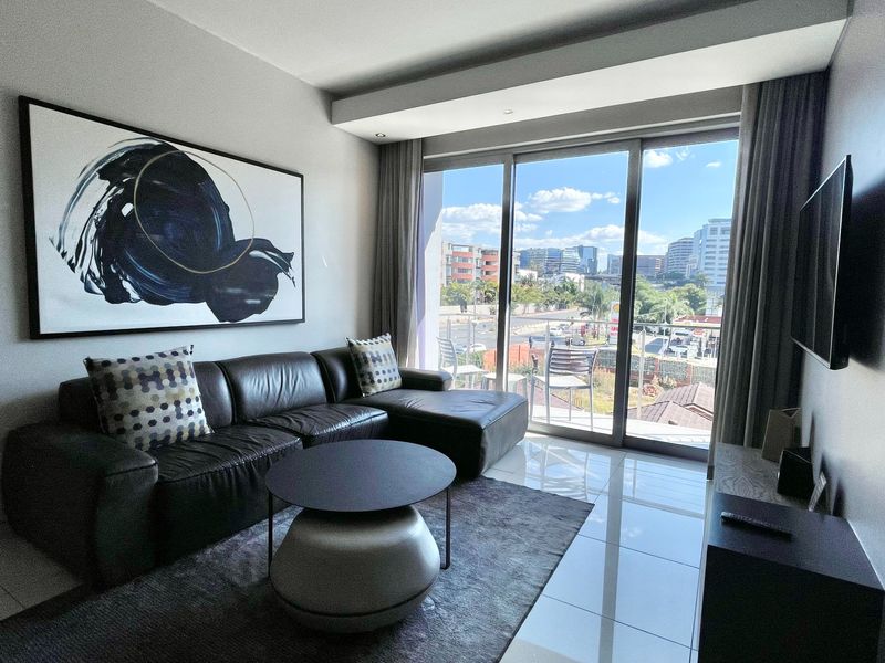 A modern living room featuring large sliding glass doors that provide natural light and access to a balcony with urban views.