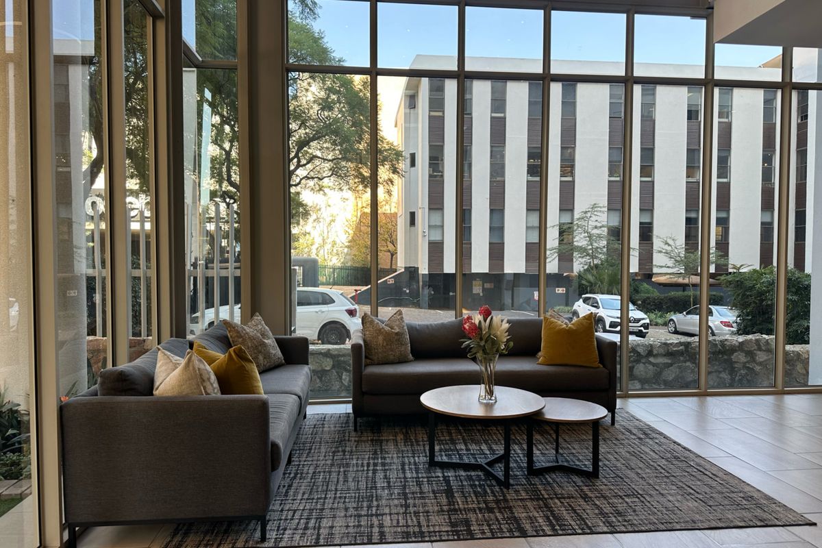 A bright, modern living area featuring floor-to-ceiling windows that provide ample natural light and an urban outlook.
