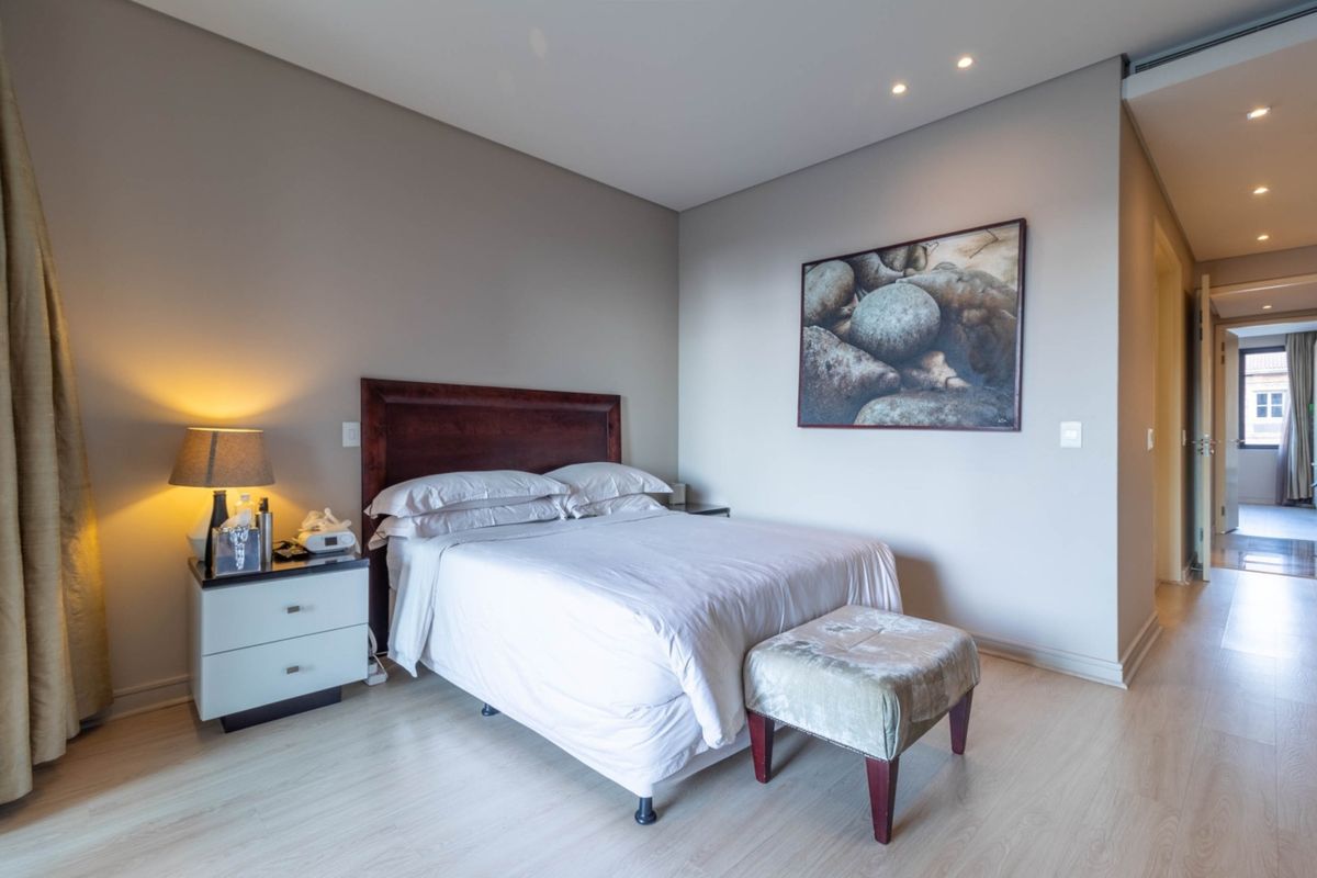 A well-maintained bedroom featuring light wood-look flooring, recessed ceiling lighting, and a neutral color palette.