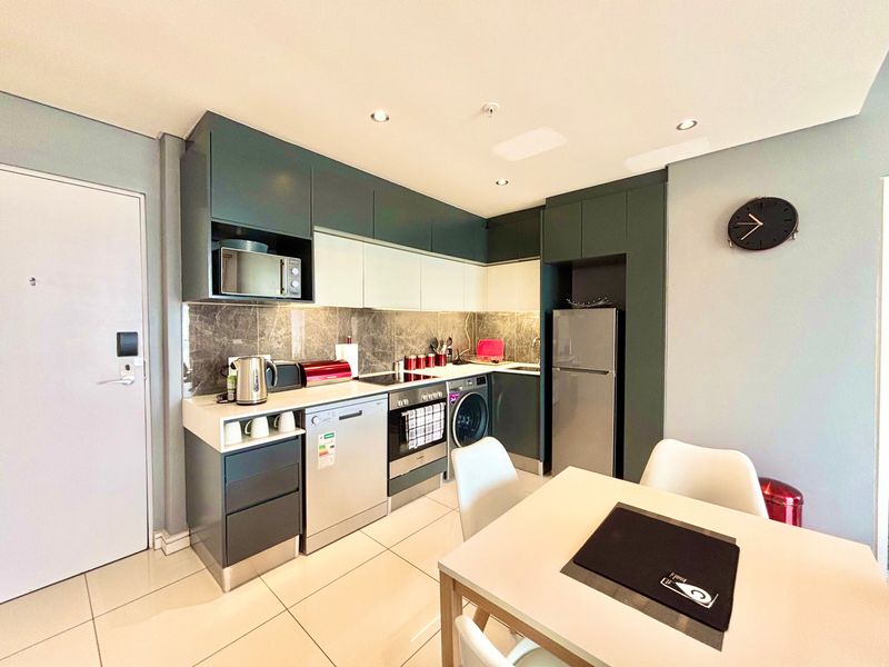 Modern kitchen featuring dark and light cabinetry, stone countertops, integrated appliances, tiled backsplash, and recessed lighting in an open-plan layout.