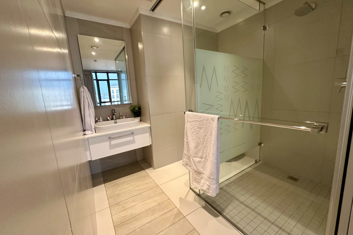 Modern bathroom featuring a wall-mounted vanity with a vessel sink, a large mirror, and a spacious walk-in shower with a glass enclosure.
