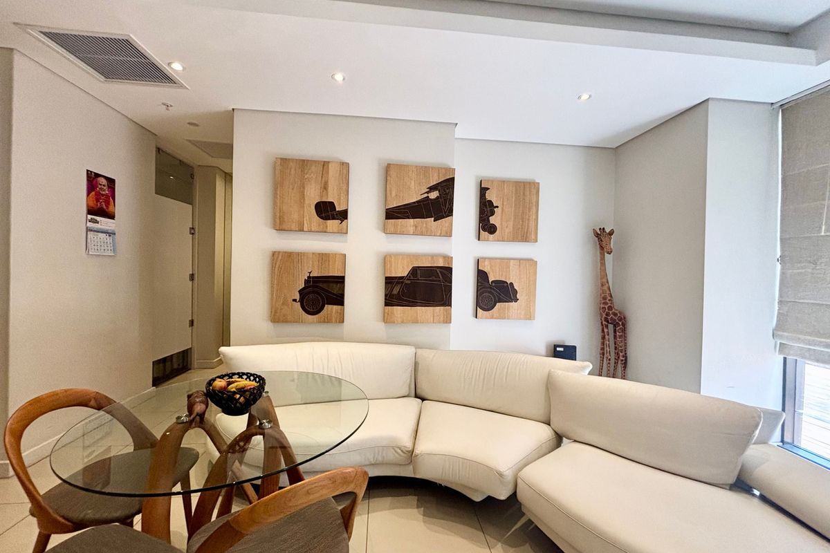 A bright living area featuring recessed ceiling lighting, tiled flooring, and a neutral color palette, creating a clean and modern atmosphere.